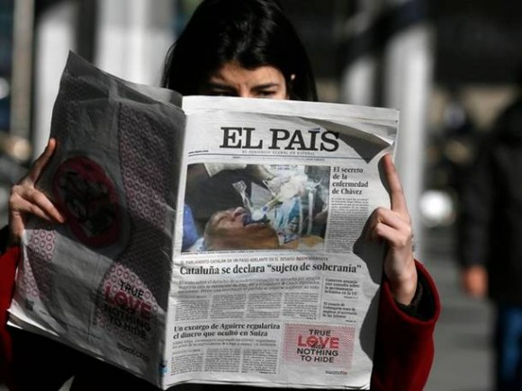 Mulher lê edição do jornal espanhol 'El País' com foto que mostra um homem entubado que uma agência de notícias havia fornecido à publicação afirmando que se tratava de Hugo Chávez. O jornal decidiu paralisar a distribuição ao constatar o erro. (Foto: Andrea Comas/Reuters)