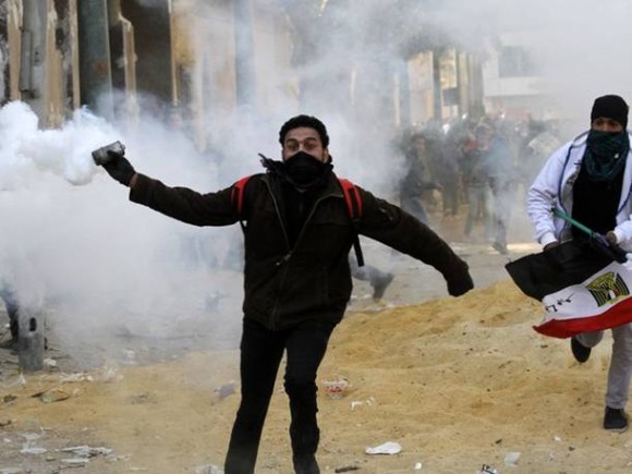 Manifestante se prepara para atirar bomba de gás lacrimogênio durante confornto no Cairo (Foto: Mohammed Abed/AFP)