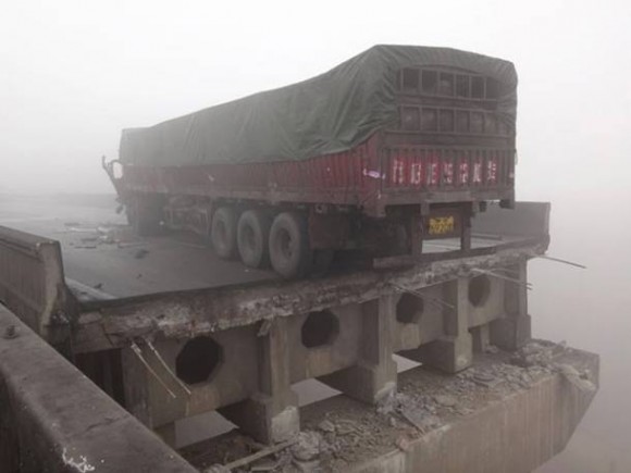 Um dos caminhões que trafegava no local da explosão ficou a poucos centimetros de cair após ponte desabar (Foto: Reuters)