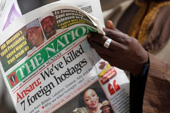 Homem lê jornal no que exibe manchete afirmando que sete reféns foram mortos, de acordo com declação do grupo islamista Ansaru (Foto: AP)