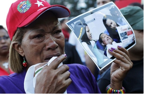 Com foto de Hugo Chávez na mão, venezuelana chora após o anúncio da morte do presidente do país (Foto: Carlos Garcia Rawlins/Reuters)