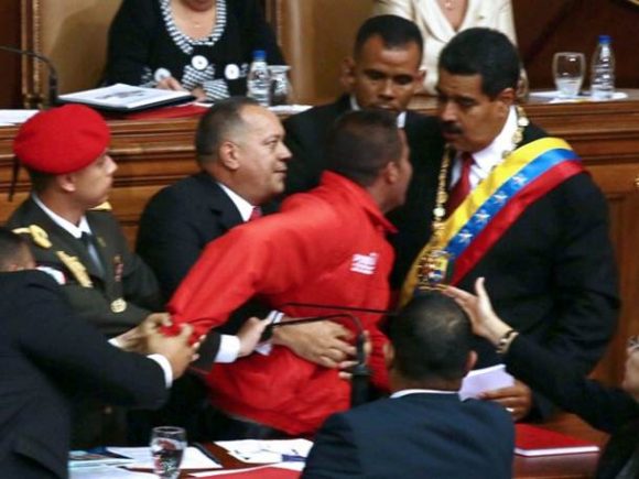 O presidente da Assembleia Nacional, Diosdado Cabello, e seguranças seguram um homem de jaqueta vermelha que tenta se aproximar de Nicolás Maduro durante a cerimônia de posse (Foto: Francisco Boza/AFP)
