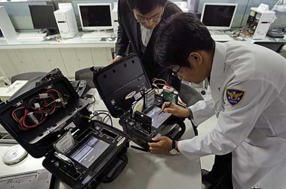 Especialistas em computadores verificam os hardwares de uma máquina infectada da rede ‘KBS’. (Foto: Lee Jin-man / AP Photo)