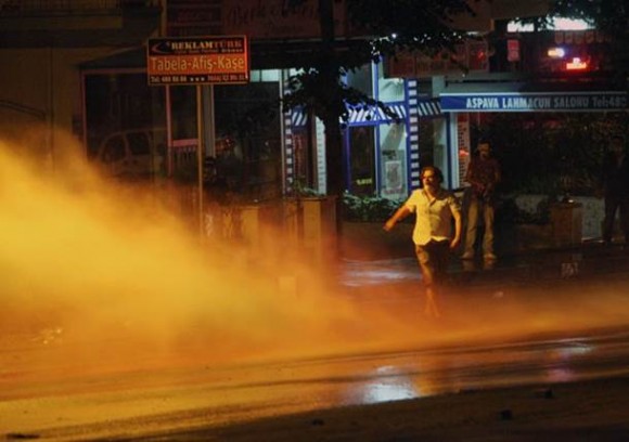 Manifestante se protege de jato d'água lançado por policial na madrugada desta sexta-feira (28) em Ancara, capital da Turquia (Foto: Adem Altan/AFP)