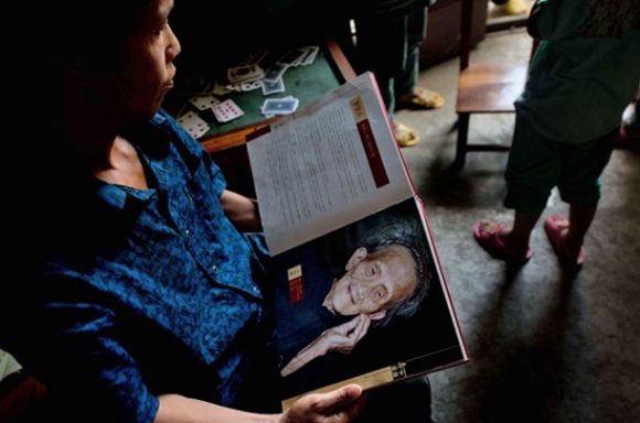 Neto de Luo Meizhen segura foto da mulher, que Segundo as autoridades chinesas tinha 127 anos ao morrer (Foto: Ed Jones/AFP)