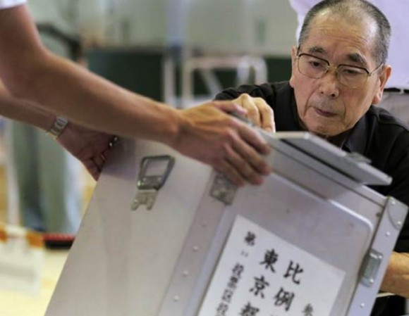 Um homem lança seu voto na casa eleições parlamentares superiores do Japão em um posto de votação em Tóquio, no domingo (21) local. (Foto: Itsuo Inouye/AP Photo)
