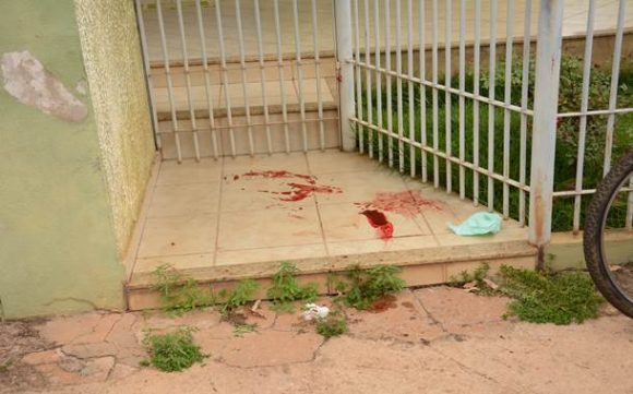 Sangue da vítima espalhado no portão de uma residência  - Foto: Varlei Cordova / AGORA MT