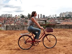 Mari anda de bicicleta no chão batido de Paraisópolis, e ao fundo a paisagem contrasta duas realidades (Foto: Marcos Mazini/Gshow)