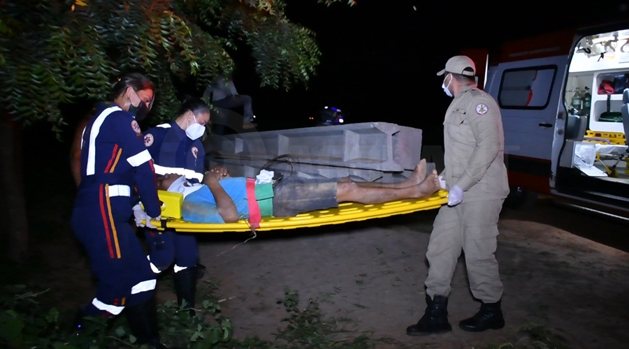 Imagem: Profissionais do Samu levando a vitima para a ambulancia Motoqueiro bate em tronco caído rua, fica ferido e é encaminhado para o hospital