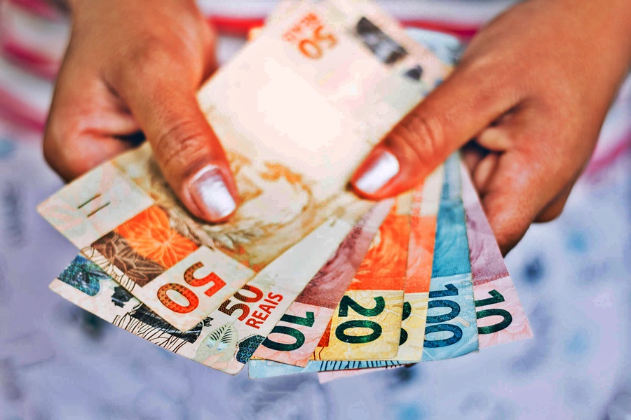 Imagem: Segurando dinheiro Abono salarial PIS/Pasep começa a ser pago com valor do novo salário mínimo